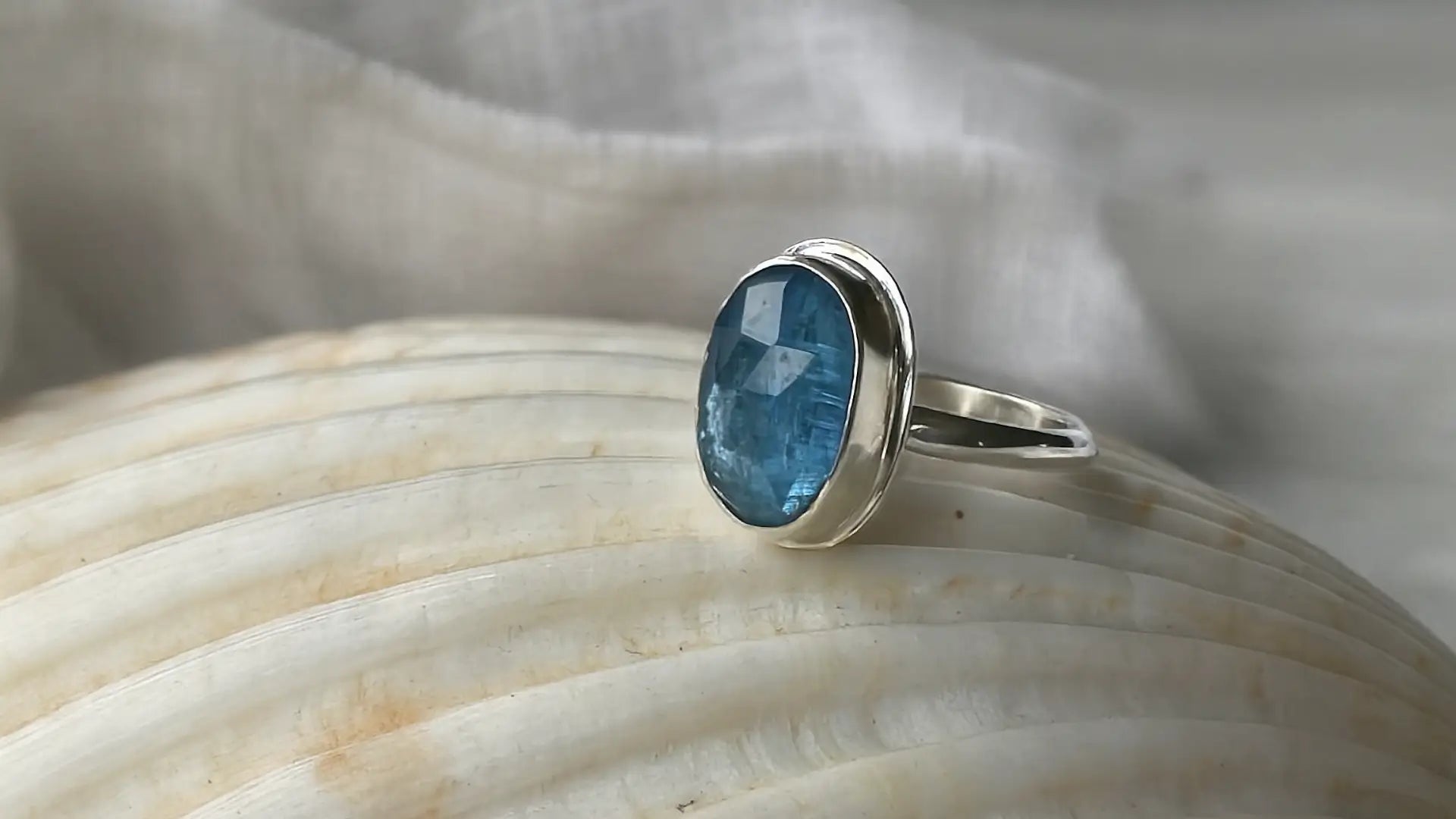 Silver ring with a blue gemstone on a shell